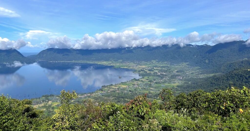 Clouds reflected in Maninjau Lake, surrounded by paddy fields and fishing villages.