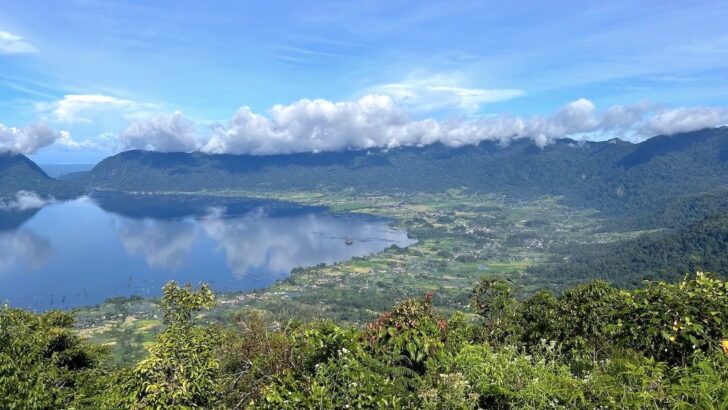 Clouds reflected in Maninjau Lake, surrounded by paddy fields and fishing villages.