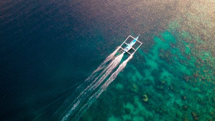 Traditional Philippines bangka boat speeds over the open ocean while diving Anilao.