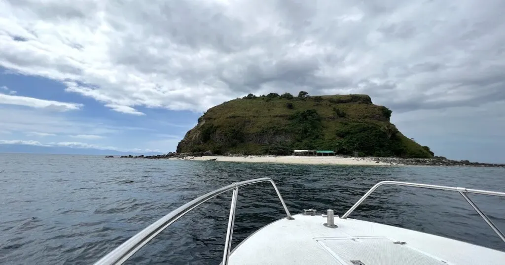 A speedboat approaches the hat-shaped Sombrero Island while diving Anilao.