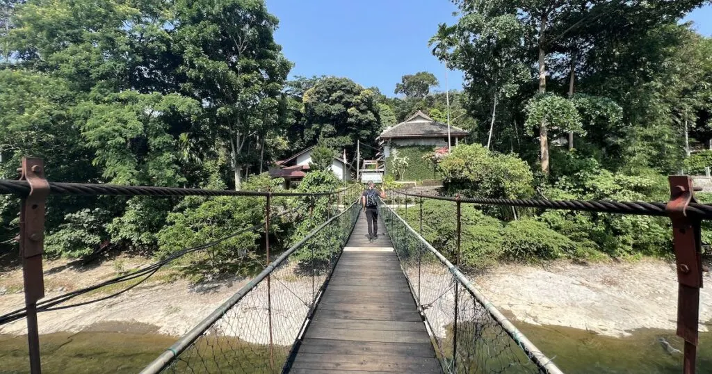 Tourist walks across a bridge over the Bohorok River in Bukit Lawang.