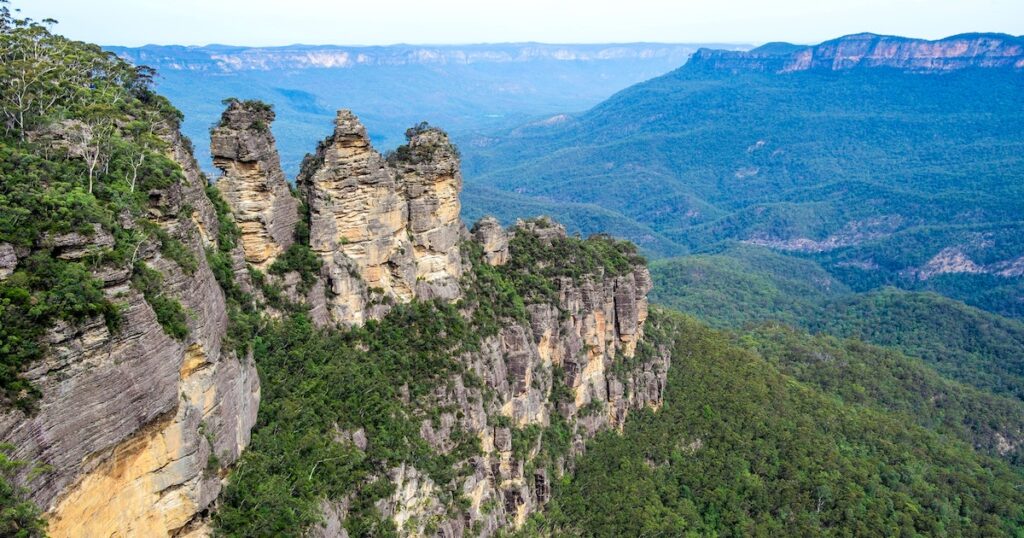 The Three Sisters in Jamison Valley, surrounded by green mountains.