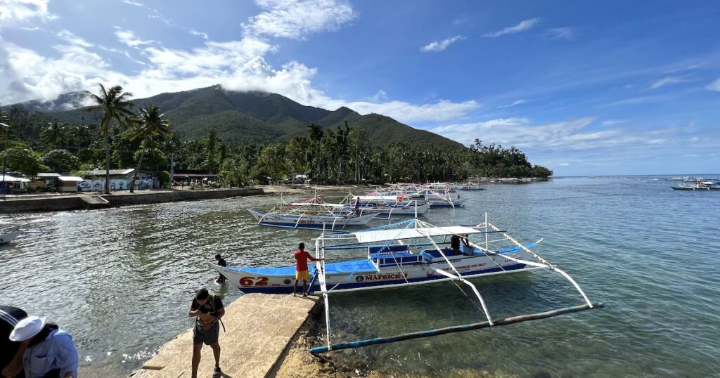 A line of traditional bangka boats wait at Sabang Port, framed by a slope with rainforest.