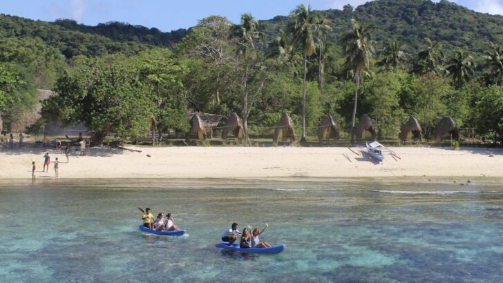 Kayaks carry tourists over shallow reef on a remote island in Linapacan in Palawan , from Coron to El Nido.