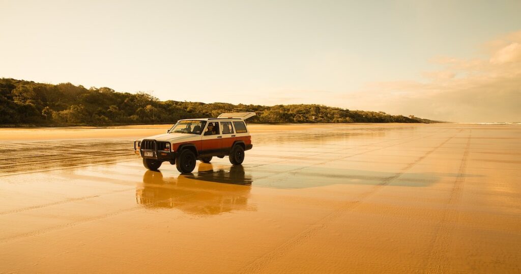 A jeep is parked on 75 Mile Beach on K'Gari Island, its boot propped open.