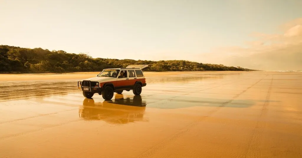 A jeep is parked on 75 Mile Beach on K'Gari Island, its boot propped open.