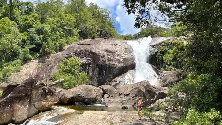 A woman walks in front of the Josephine Falls waterfall Wooroonooran on a Cairns to Mission Beach road trip.