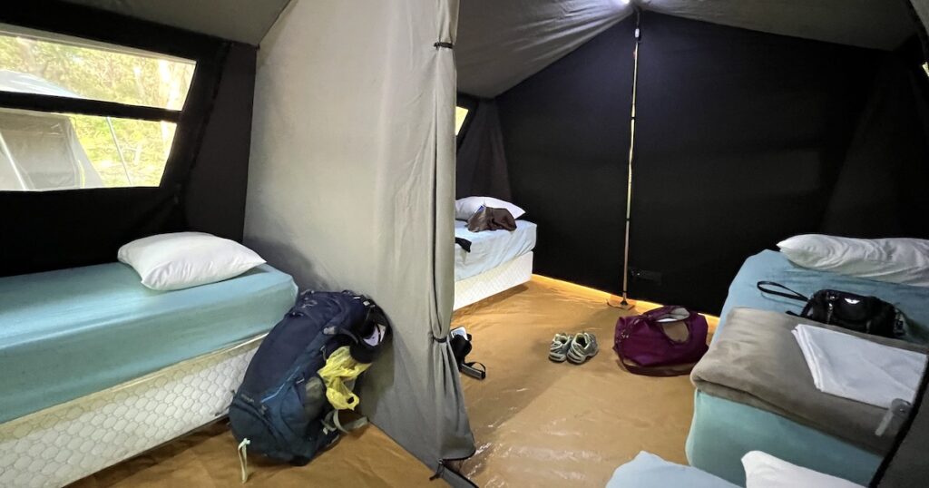 Backpacks rest at the foot of four beds in a tent on Fraser Island.