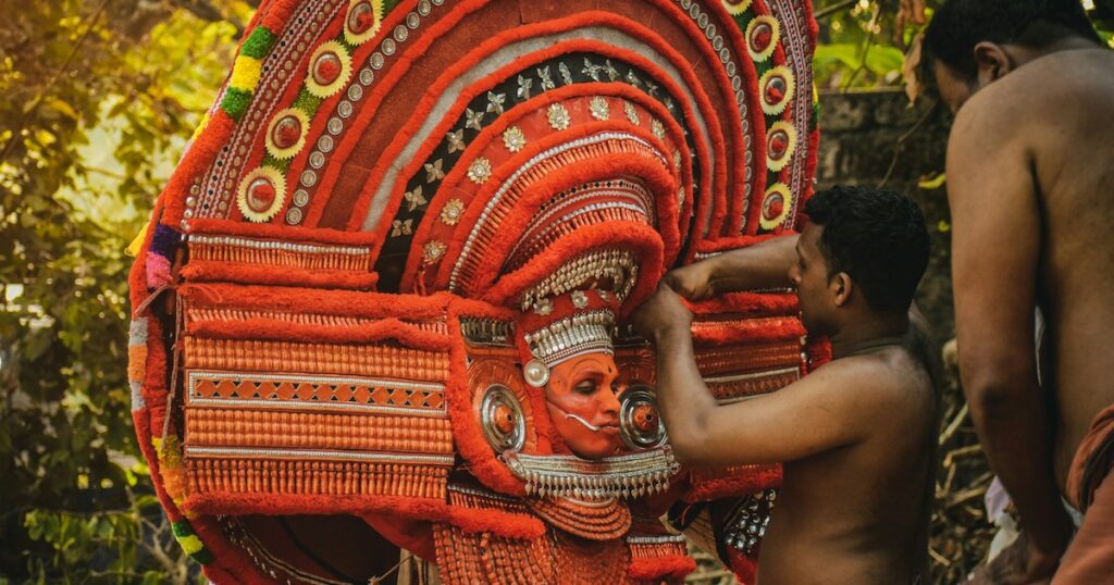 A man wearing red paint and costume performs a ritual in Kunnar, Kerala.