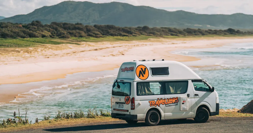 The Travellers Autobarn Kuga Campervan parked next to a long, sandy beach in Australia.