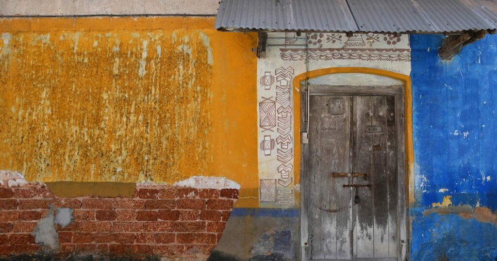 Old wall painted yellow, blue and white in Fort Kochi.