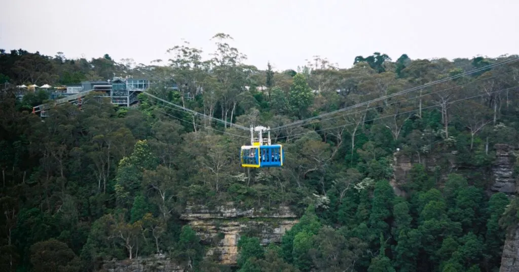 A blue cable car hovers over the forested Jamison Valley at Scenic World.