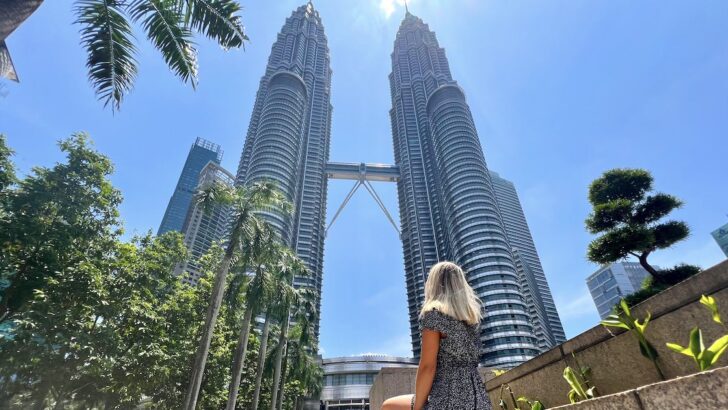 Woman sits at the bottom of the Petronas Towers, one of the best places to visit on a Kuala Lumpur itinerary.
