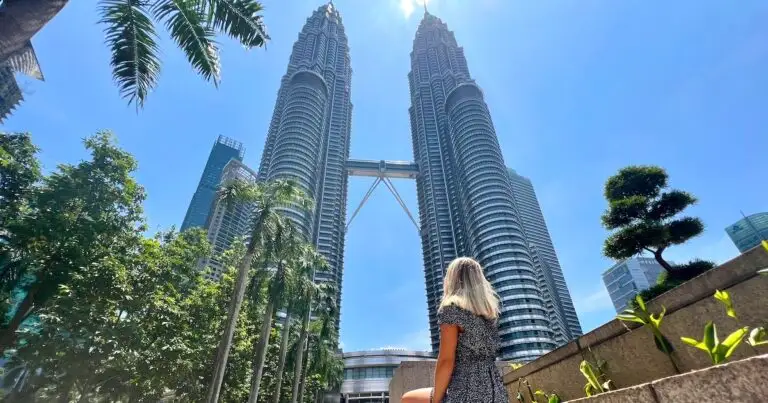Woman sits at the bottom of the Petronas Towers, one of the best places to visit on a Kuala Lumpur itinerary.