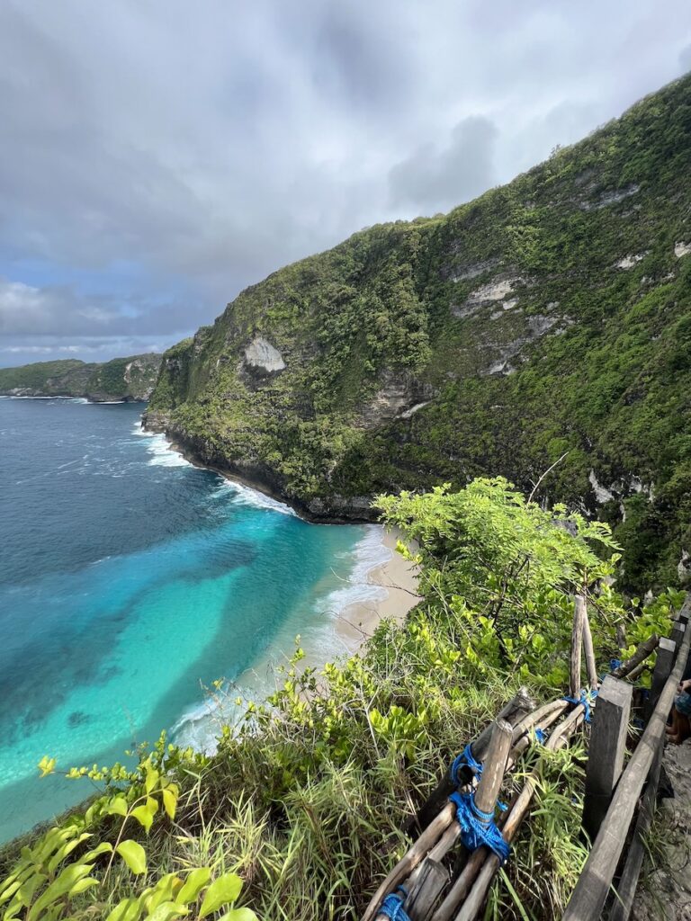 View down to Kelingking Beach from the steep hiking trail with bamboo railings.