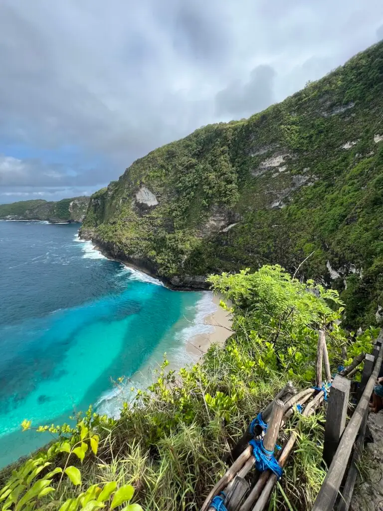 View down to Kelingking Beach from the steep hiking trail with bamboo railings.