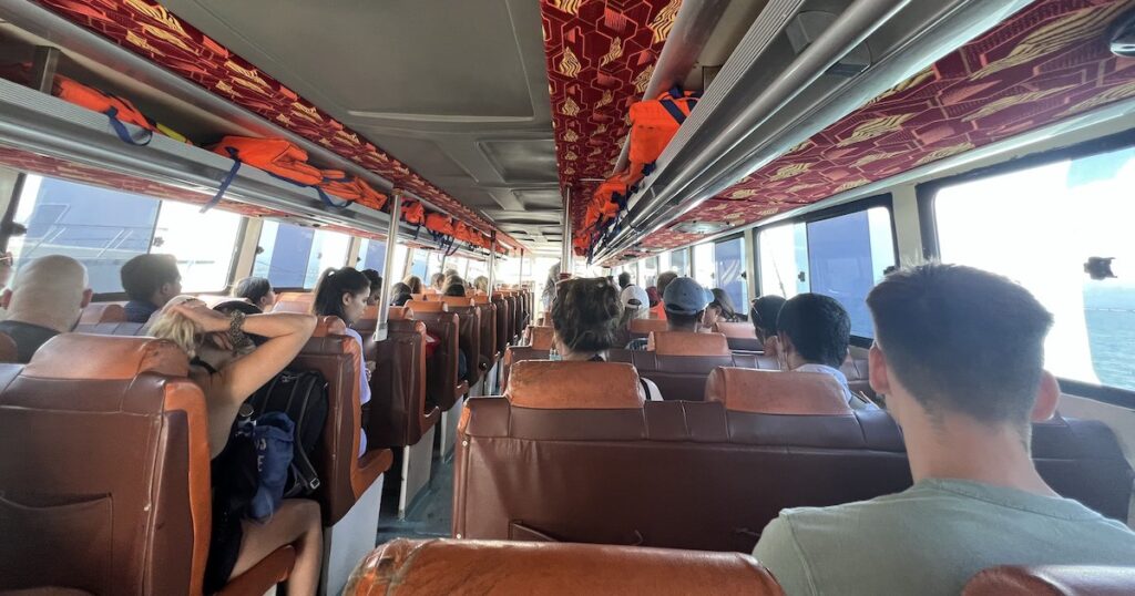 Passengers seated on leather chairs on a fast boat from Sanur to Nusa Penida.
