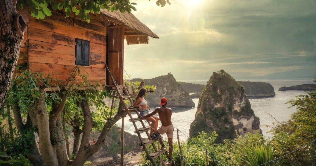 A couple sit on the staircase at the Rumah Pohon treehouse in Nusa Penida.