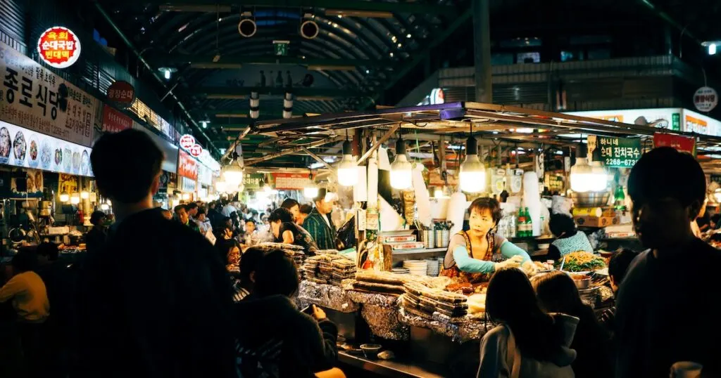 A woman prepares food at one of many stalls at the crowded Gwangjang Market in Seoul, which is packed with crowds.